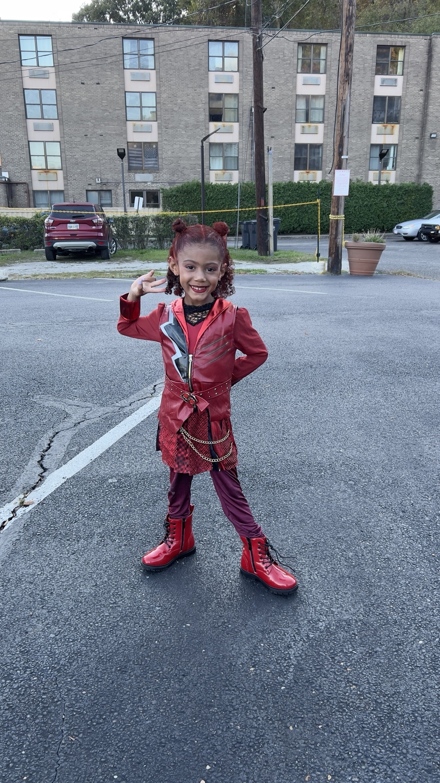 Child posing in a red Halloween costume with boots and playful makeup